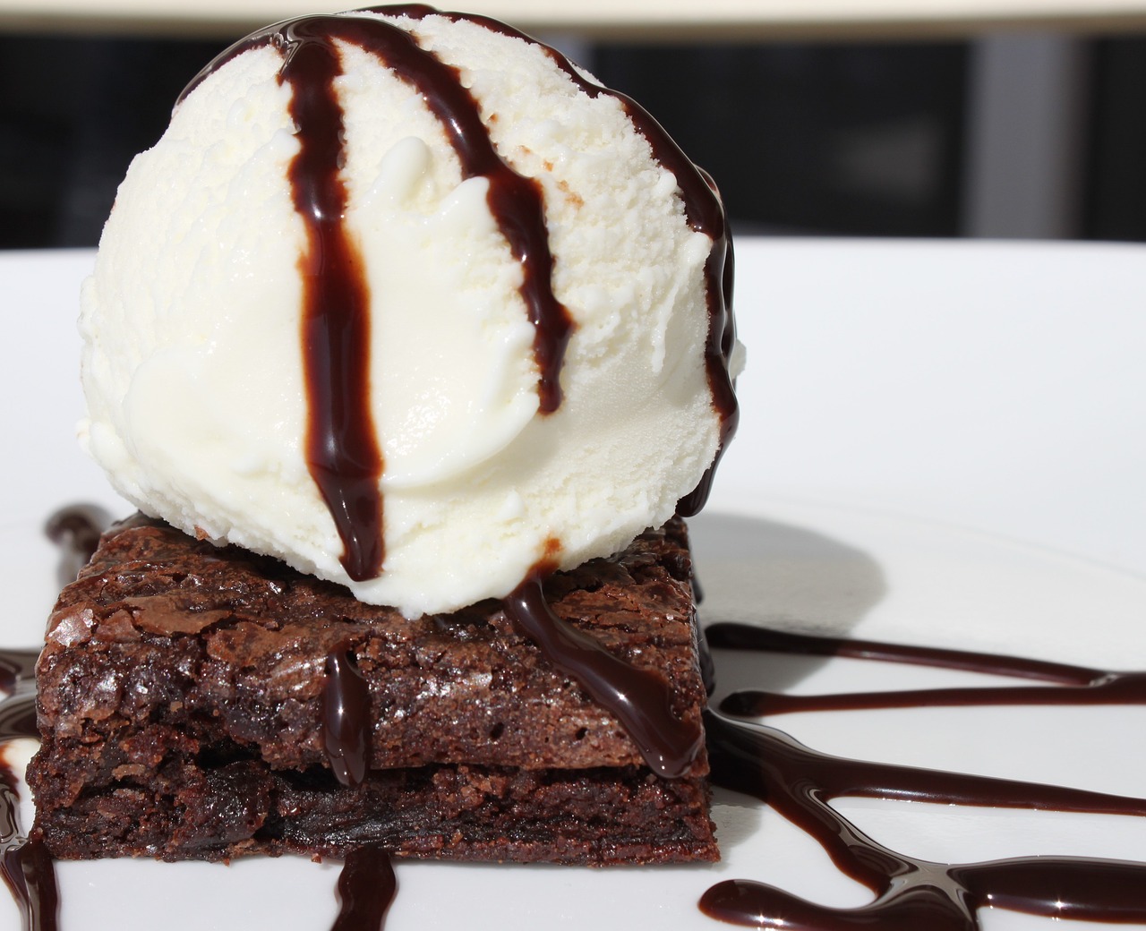 a warm chocolate brownie covered in chocolate syrup with ice cream dripping down